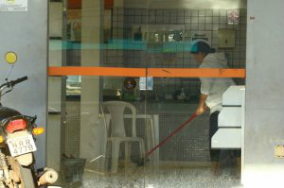 Funcionária limpando, na terça-feira de manhã, o sangue que ficou na conveniência (Foto: André Bittar)