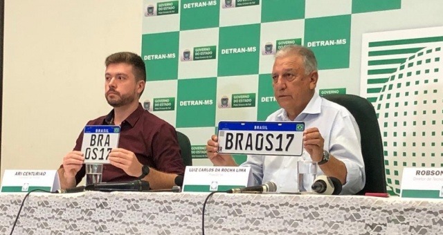 Ari Centurião (esq) da comissão de placas e Luiz Rocha, diretor-presidente do Detran/MS, apresentam novas placas, em coletiva realizada hoje (Foto: Jones Mário)