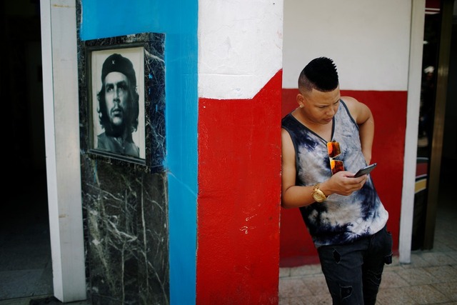 Jovem verifica celular em Cuba perto de um hotspot de internet — Foto: Tomas Bravo/Reuters