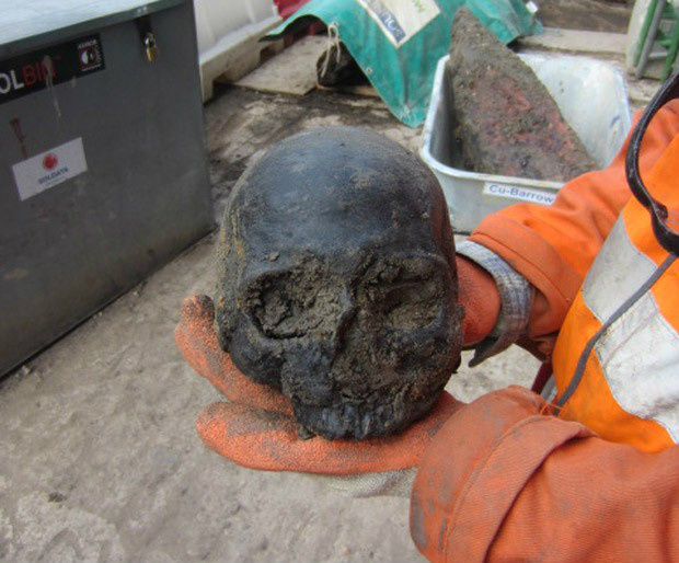Funcionário mostra um dos 20 crânios encontrados durante obra de transporte subterrâneo em Londres. (Foto: Crossrail Limited/Divulgação