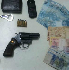O revólver, as munições e o dinheiro apreendido pela polícia