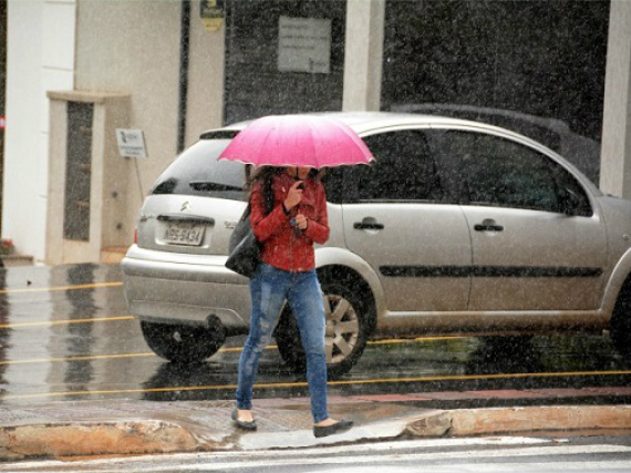 Mulher protege-se de chuva em Campo Grande - Foto: Álvaro Rezende / Correio do Estado