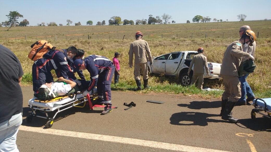 Médico recebendo os primeiros socorros de equipes de bombeiros e Samu e veiculo tombado além rodovia (Foto: Nelson Roberto)