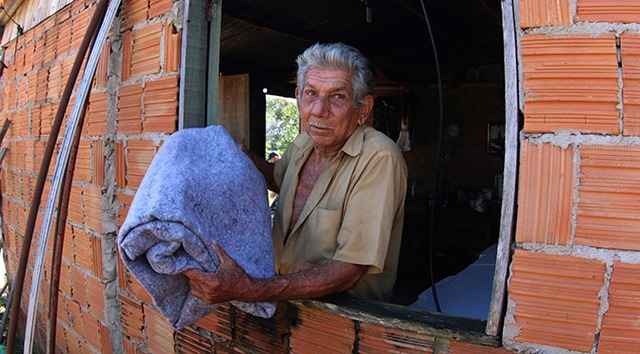 Homem recebe cobertor doado pelo governo de MS em Corguinho (Foto: Chico Ribeiro/MS)