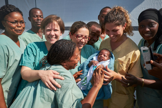 A bebê no colo de Nubia Aguiar, enfermeira brasileira que ajudou a atendê-la na Guiné (Foto: Sam Phelps/Médicos sem Fronteiras)