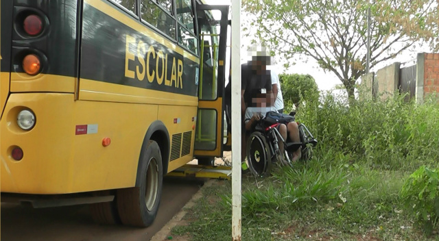 Monitor conduz cadeirante até o ônibus, passando por matagal na calçada defronte a escola. Foto: Rádio Caçula.