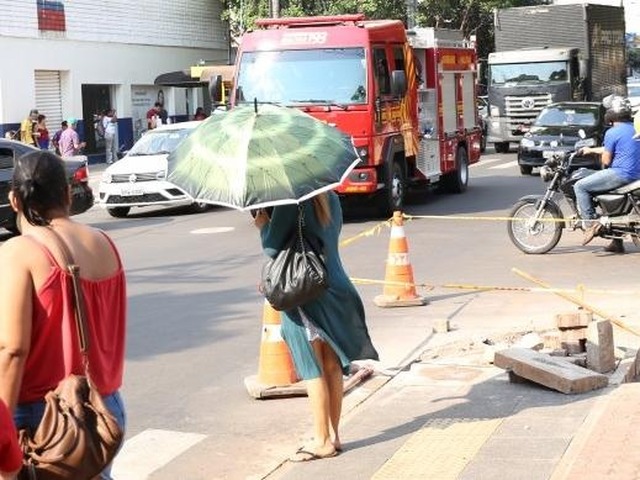 Mulher se protege do sol na Afonso Pena, enquanto Corpo de Bombeiros segue para apagar mais uma queimada em Campo Grande. (Foto: Paulo Francis)