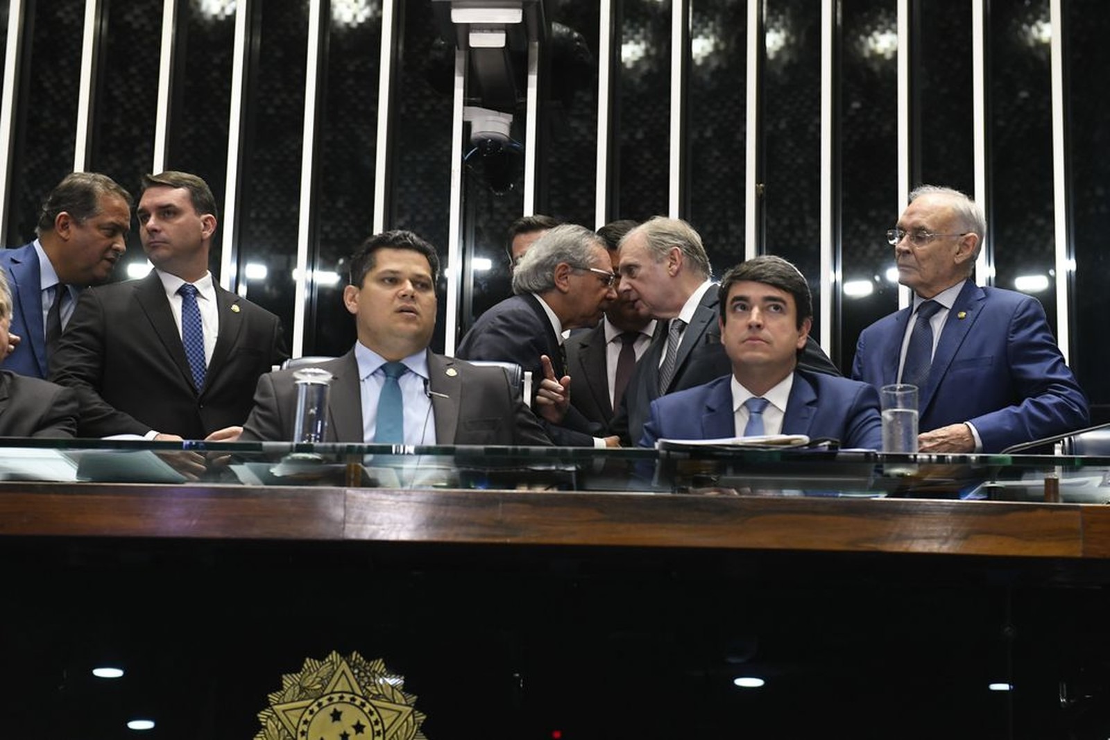O presidente do Senado, Davi Alcolumbre (DEM-AP), durante sessão de votação dos destaques da reforma da Previdência; ao fundo, o relator do texto, senador Tasso Jereissati (PSDB-CE), conversa com o ministro da Economia, Paulo Guedes. Foto: Roque de Sá/Agência Senado.