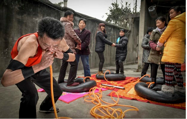 Nie Yongbing faz esforço para encher pneus com pessoas em cima usando o nariz, durante uma performance realizada em sua casa na China (Foto: Stringer/Reuters)