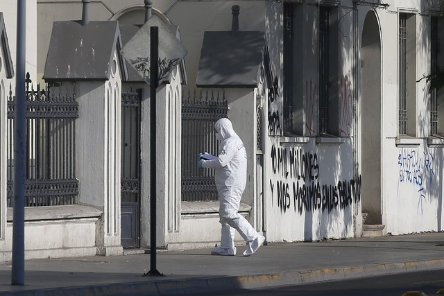 Policiais examinam cena de ataque no Chile. Pelo menos três igrejas em Santiago foram danificadas a poucos dias da visita do papa ao país (Foto: Pablo Vera/AFP)
