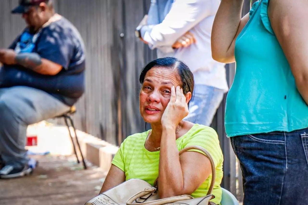 Professora em frente à delegacia é amparada por amigos. Foto: Henrique Kawaminami/ Campo Grande News.