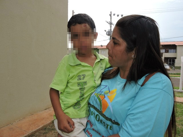 Criança que pulou do 1º andar com hematoma na cabeça, sendo amparada por vizinhos. Foto Rádio Caçula 